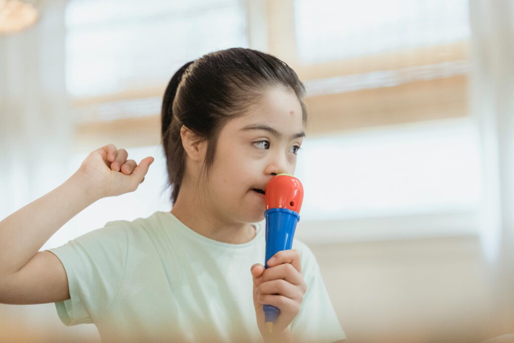 Young girl singing into a toy microphone, expressing joy and creativity indoors.